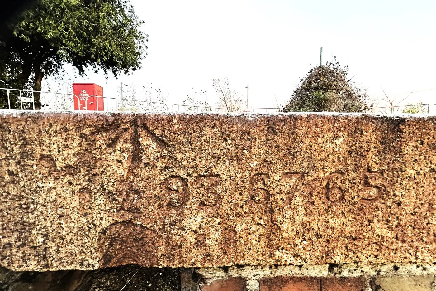 THE ANSWER CARVED IN STONE: The arrow represents the surveyors mark and the three numbers indicate that the distance to Spencer Street from Euroa is 93 miles, 67 chains, and 65 links. There are 80 chains in a mile and 100 links in a chain. But, of course.