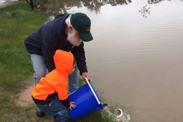 STARTING YOUNG: Matthew Dolphin is helped by Henry Hoornweg to release some rainbow trout into the Arboretum dam.