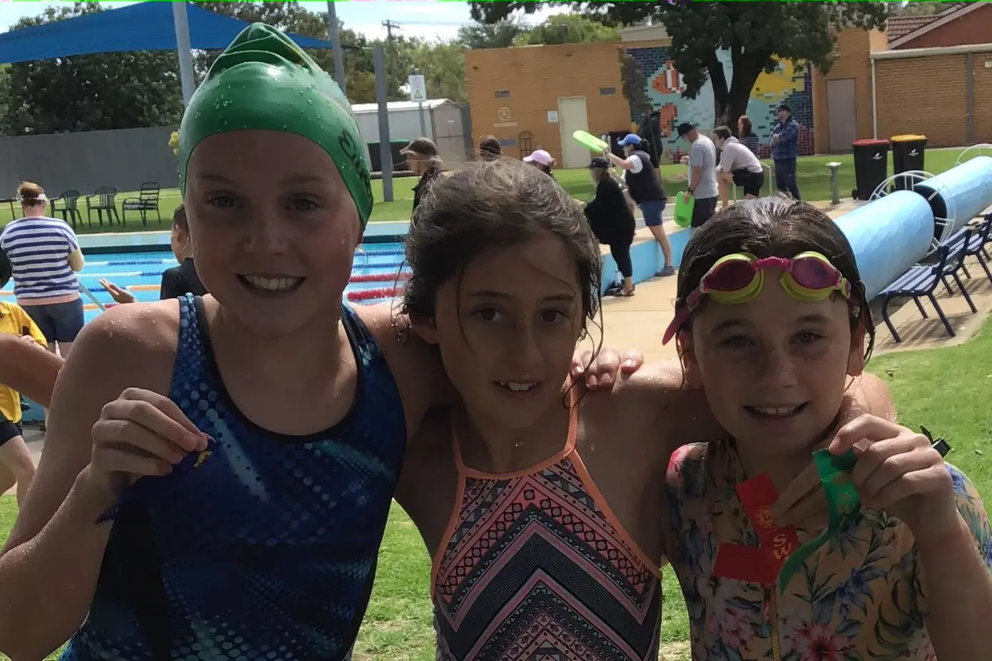 PROUD OF EFFORTS: Kadey Macklin (left), Macey Watson and Sienna Burke show off their ribbons after the 12/13 year backstroke.