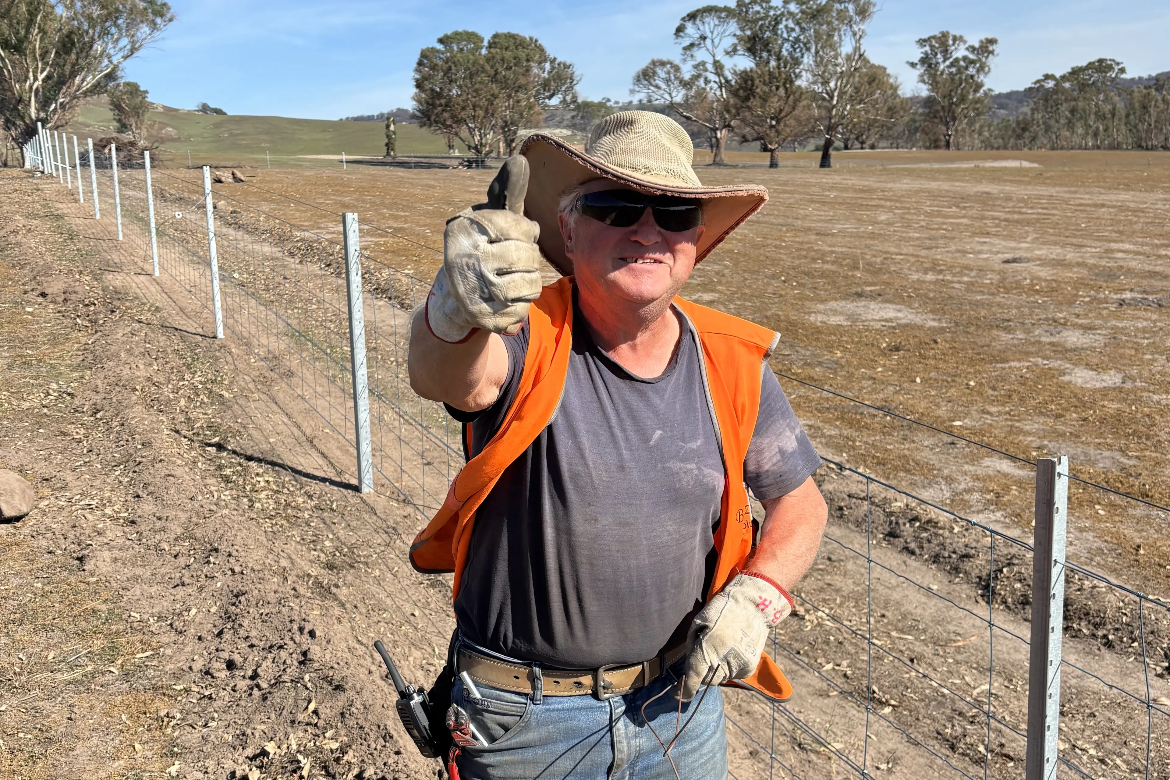 <p>THUMBS UP: BlazeAid volunteer Bert, from Ireland, beside a newly rebuilt fence on a Creightons Creek property. He plans to return in spring. PHOTO: Brian Kelly</p>\\n